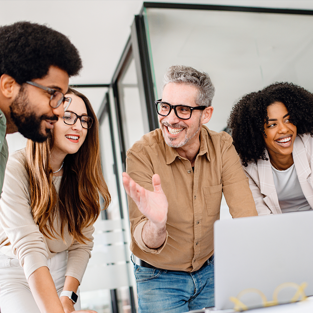 Group of office workers collaborating around an open laptop