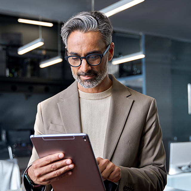 AI platforms: man standing in an office tapping a tablet in his hands