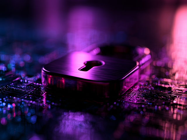 A padlock with a large keyhole lying flat on a computer board with purple lighting
