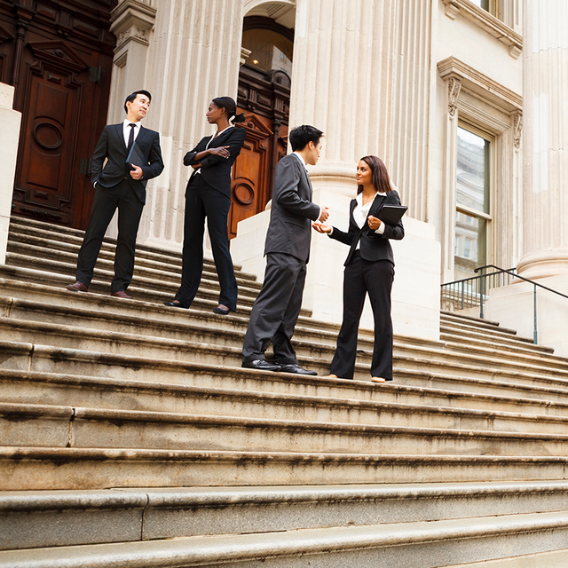 Four employees standing on the steps outside a government building