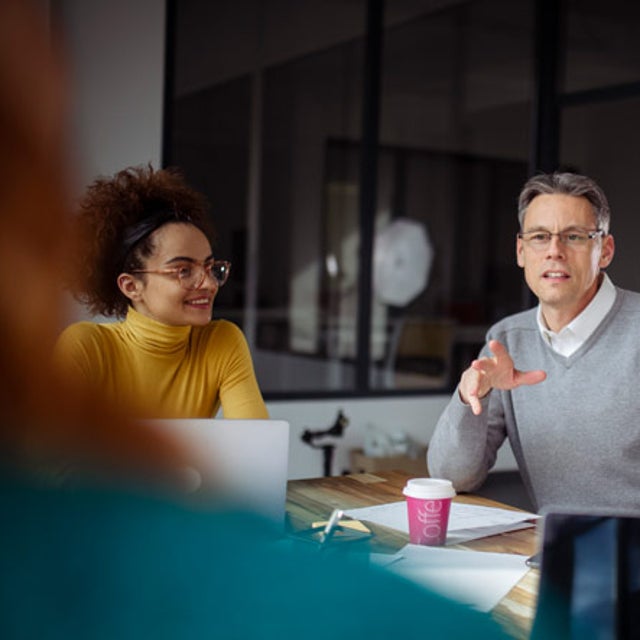 A group of workers in discussion around a conference table