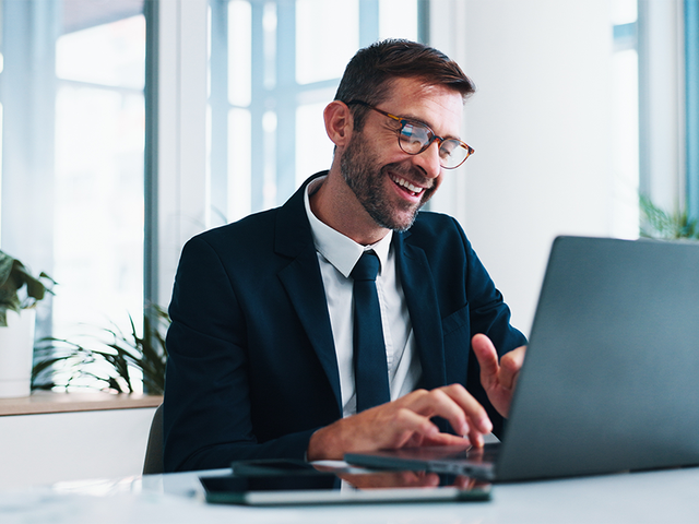 Smiling male business leader working on a laptop