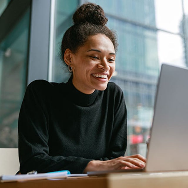 Woman smiling at an open laptop in a modern city office