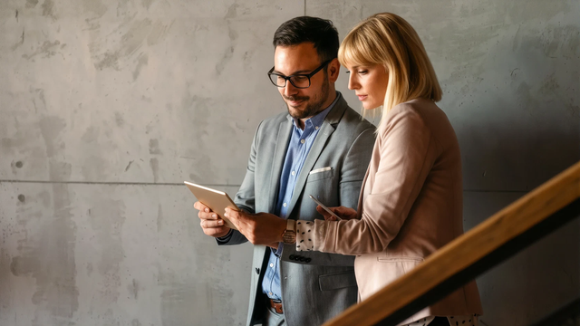 Male and female walking down the stairs looking at a tablet