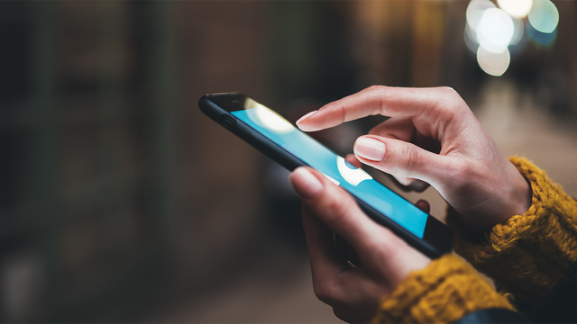 Close-up of two hands holding and using a phone