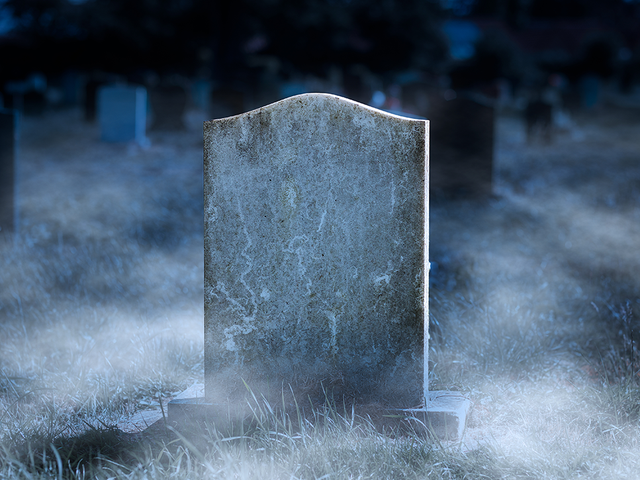 Blank gravestone surrounded by fog and other gravestones