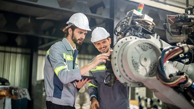 Two factory workers inspecing a machine