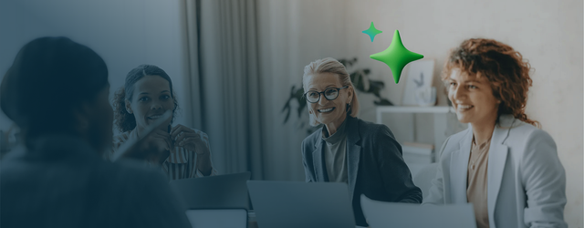 A small group of office workers sitting together at a table with their laptops.