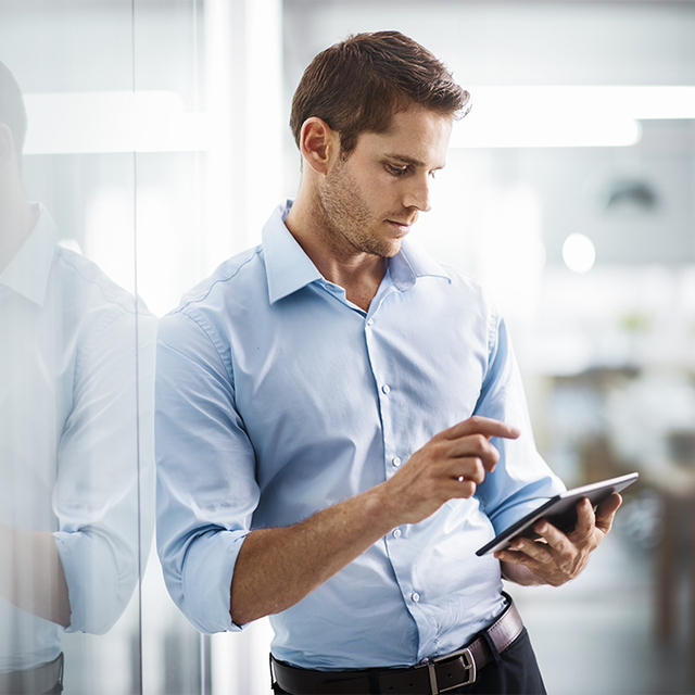 Man working on a tablet while standing in a bright office