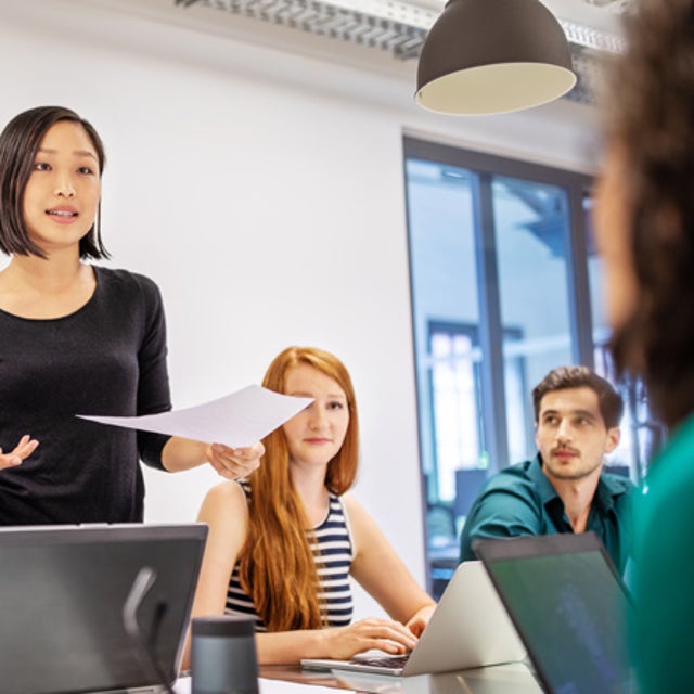 Woman leading discussion in a conference room while workers look on