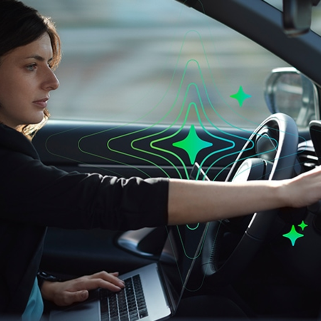 Woman using a laptop in the driver's seat of a car