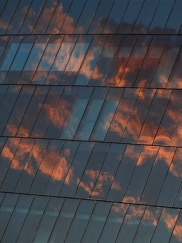Architecture of glass building with reflection of sky sunset