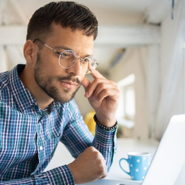 Man in glasses looking intently at open laptop