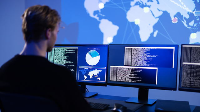 Man working on three computer monitors 