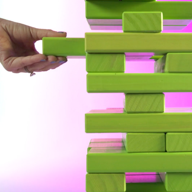 A hand removing a plank from a Jenga tower