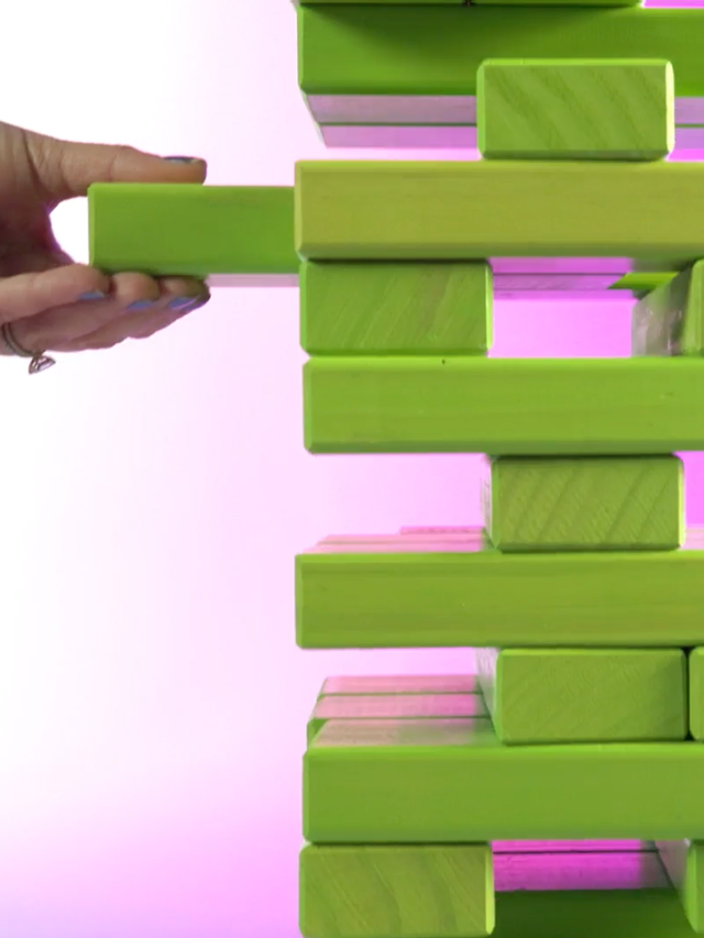 A hand removing a plank from a Jenga tower